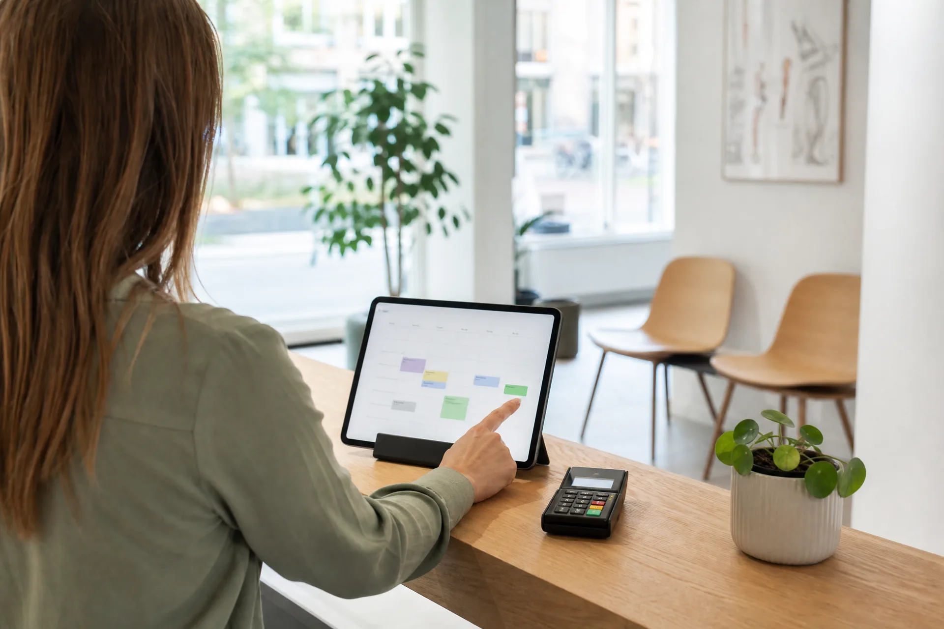 AI-gegenereerde reportagefoto: receptioniste van een fysiopraktijk in Groningen bevestigt een online boeking in de weekagenda op de tablet aan de balie